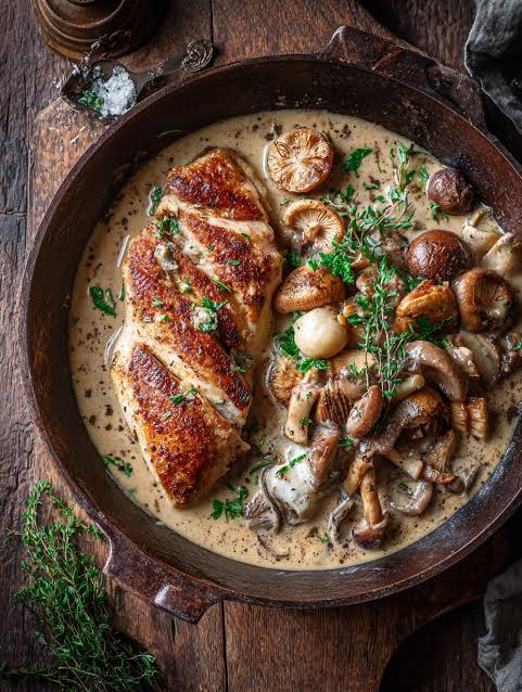 Seared chicken breast with sautéed wild mushrooms in a creamy truffle sauce, served in a cast-iron skillet